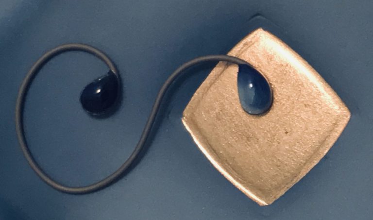 detail image of a saturated blue saucer with a gold enamel center and a swirly wire with kiln-fired jewels