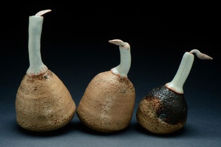 Three vessels in taupe, blue, and black with tongue shapes coming out of the top