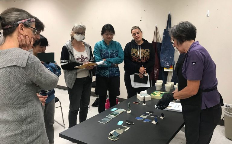 Image of a class and instructor looking at test tile results from sustainable glazes 