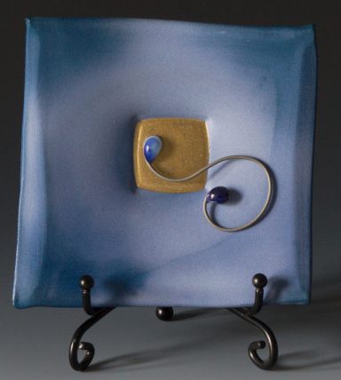 CLose up image of a blue sculptural saucer, nichrome swirly wire with Kiln Jewels and gold enamel. with 
