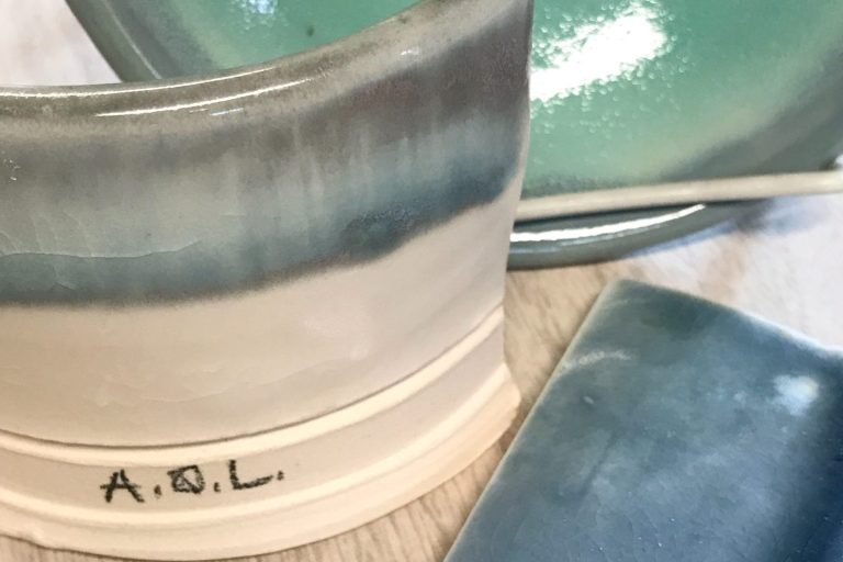 Two ceramic test tiles and one bowl showcasing sustainable glazes. The tiles display beautiful subtle colors of blue, green, and gray